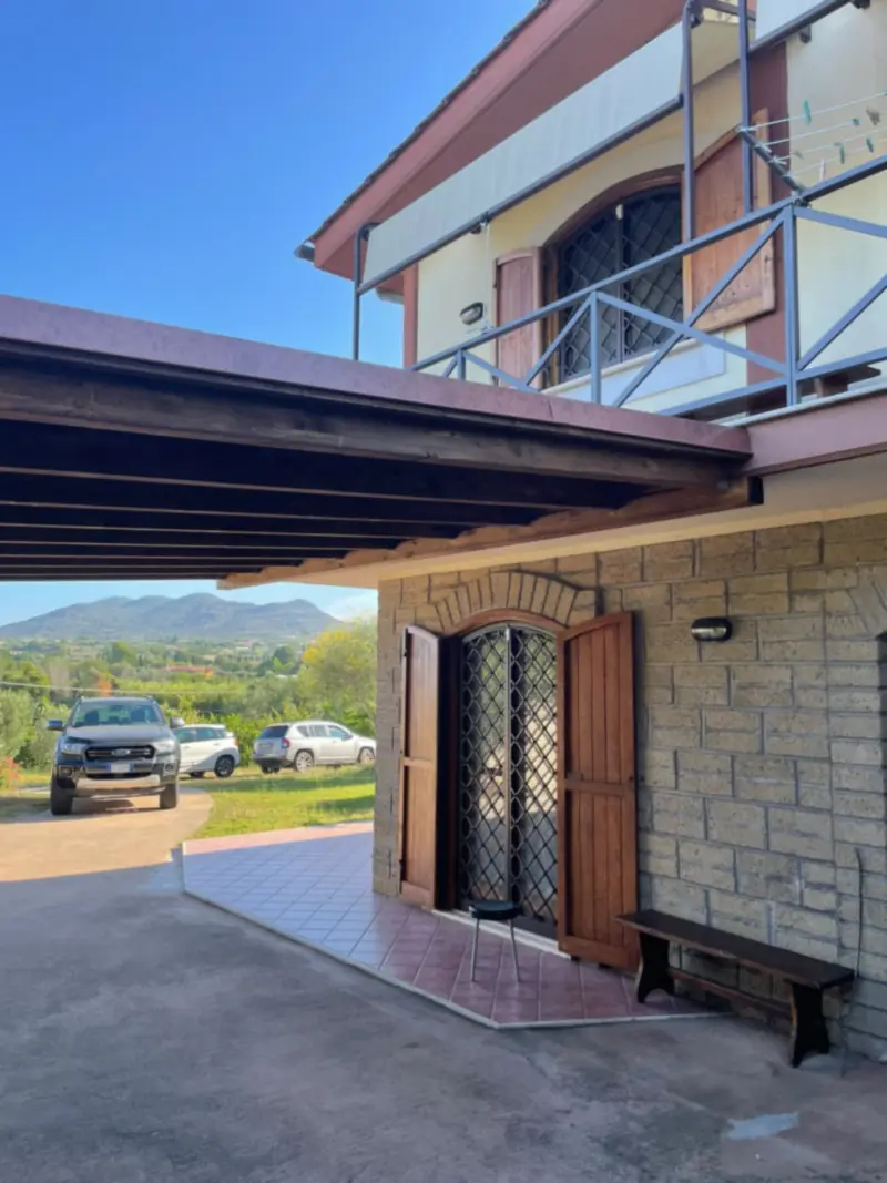 Ingresso di una casa con rivestimento in pietra e tettoia in legno