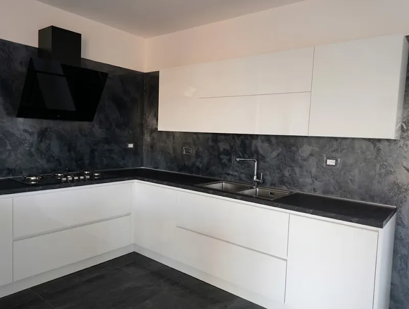 Cucina di un appartamento ristrutturato, con mobili bianchi e piano scuro