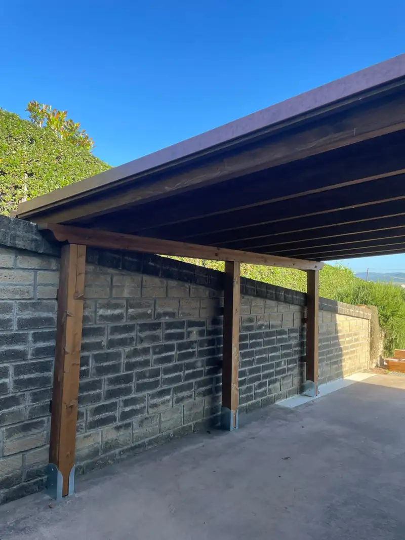 Tettoia in legno addossata a un muro in blocchi di pietra