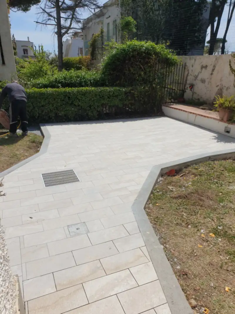 Vialetto esterno in lastre di pietra chiara, accanto al giardino
